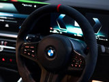 Steering wheel with a BMW logo is centered, surrounded by digital screens displaying vehicle information, inside a modern car's interior. Ambient lighting and dashboard controls enhance the sleek, futuristic environment.