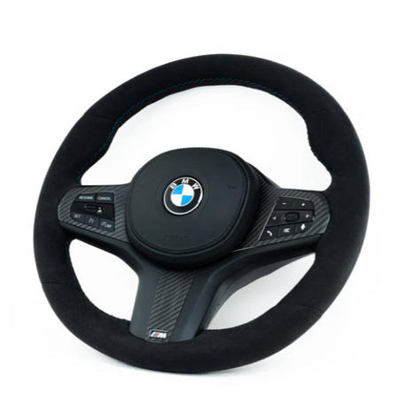 A black BMW steering wheel with control buttons, featuring a carbon fiber design and "M" logo, is set against a plain white background.