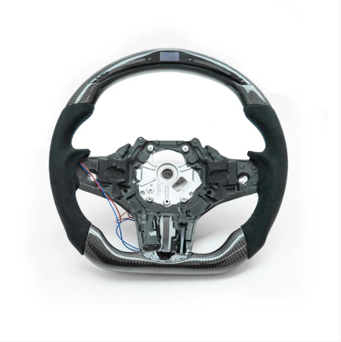 A car steering wheel, featuring carbon fiber detailing and exposed wiring, is set against a plain white background.
