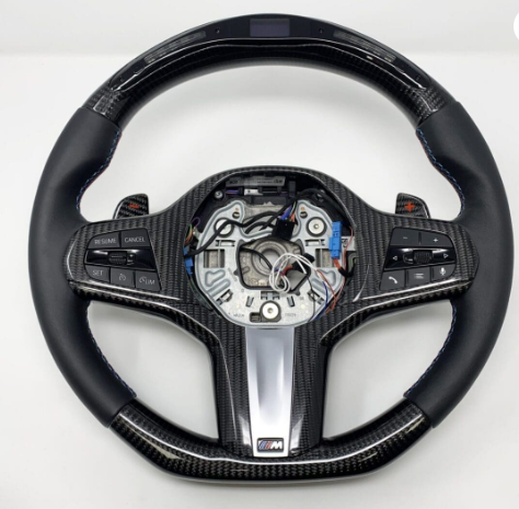 A carbon-fiber and leather car steering wheel, with integrated buttons and exposed wiring in the center, set against a plain white background.