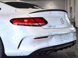 A white Mercedes-Benz AMG car is stationary in a well-lit indoor showroom. The emphasis is on its rear, featuring sleek taillights, a glossy finish, and dual exhausts.