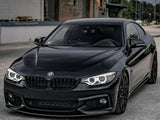 A sleek black BMW car is parked in front of a weathered brick building with an industrial setting, featuring distinct curved headlights and alloy wheels.