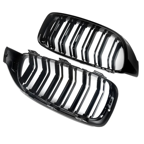 Two black, glossy car grilles with vertical slats are positioned side by side against a white background, showing their shiny surfaces and curved design.