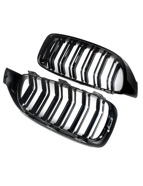 Two black, glossy car grilles with vertical slats are positioned side by side against a white background, showing their shiny surfaces and curved design.