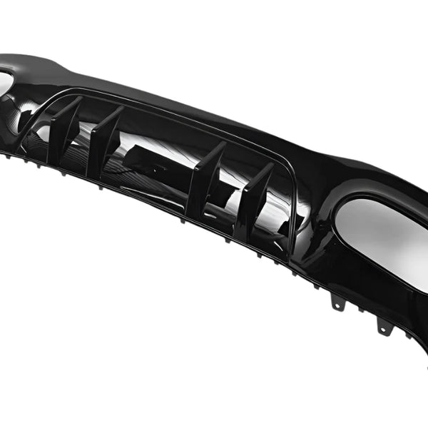 A glossy black car bumper with angular fins and aerodynamic design, lying on a plain white background.