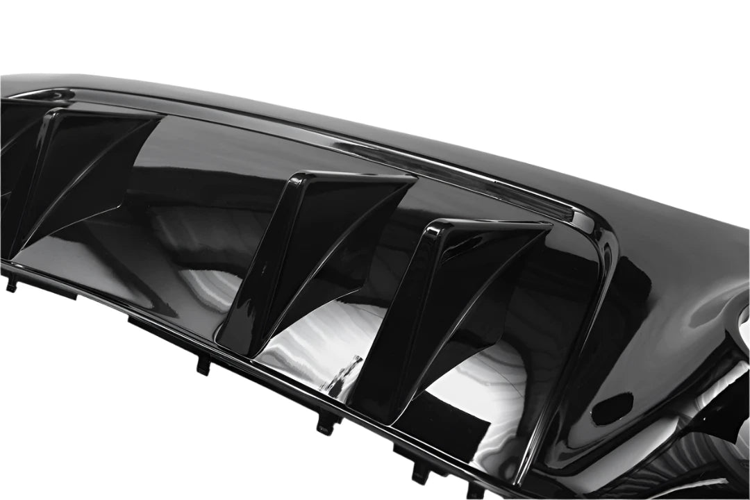 Shiny black car part with multiple fins, likely a diffuser or spoiler, reflecting light; positioned against a plain, neutral background.