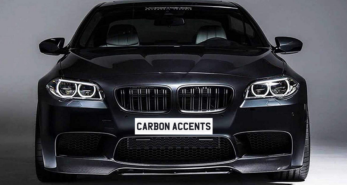 A black car with illuminated headlights sits in a studio setting. The license plate reads "CARBON ACCENTS." The car has a sleek, modern design.