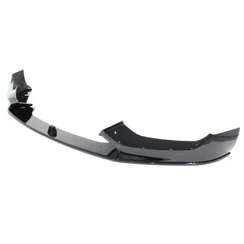 A glossy black car front bumper lip sits on a plain white background, featuring a sleek, aerodynamic design with curved edges and mounting points.