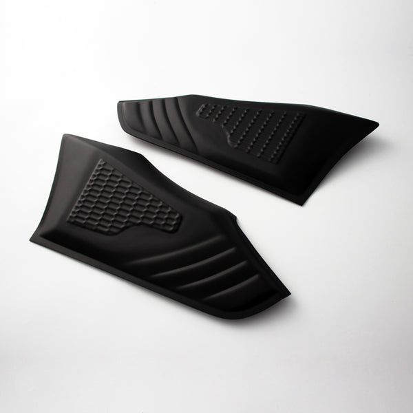 Two black rubber grip pads with textured patterns are placed on a light surface. Each pad features a distinct grid and ribbed design, typically used for vehicle or equipment grip enhancement.