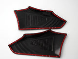 Two black plastic panels with textured surfaces, outlined by red trim tape, are positioned side by side on a plain white background.