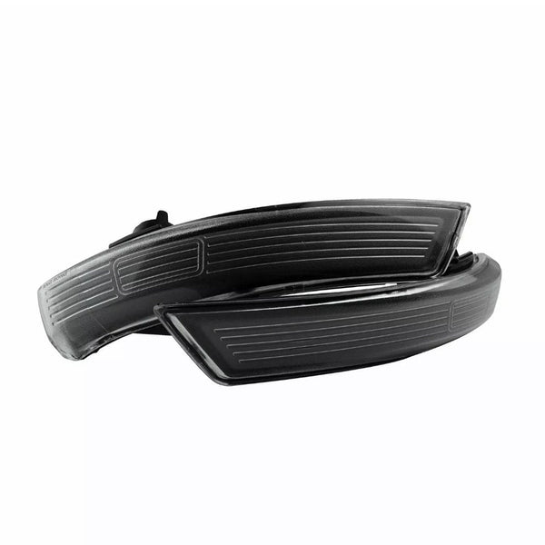 Two black, curved automotive side mirror indicators, resting on each other, have horizontal engraved lines. They are isolated on a white background, showcasing modern design elements.