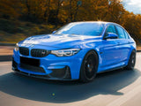A blue car drives quickly down a road, surrounded by autumn trees with golden leaves under a cloudy sky.