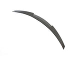 A curved, dark-colored blade-like object lies flat on a plain white background. It features a smooth surface with slightly angled edges, suggesting a sleek, aerodynamic design.