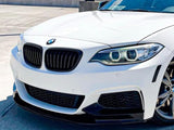A white BMW car is parked, showcasing its front grille and headlights, in a sunny, open parking lot with a concrete barrier in the background.
