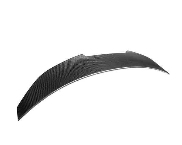 A sleek, curved black car spoiler made of carbon fiber sits isolated against a plain white background, emphasizing its aerodynamic design.