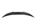 A curved, elongated carbon fiber spoiler with a sleek design lies against a plain white background.