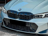 A light blue BMW car front is parked on a concrete surface. It features a prominent grille with a distinctive honeycomb design and angular headlights.