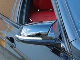 A sleek car side mirror reflects cloudy skies, attached to a black vehicle. The car's window is open, revealing a vivid red interior. The background shows a brick wall.