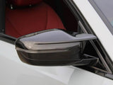 A glossy black side mirror is attached to a white car, with a visible red interior seat in the background.