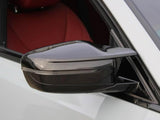 Side mirror with a sleek design attached to a white vehicle, facing outward. The interior features a red seat, visible through the window.