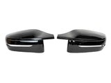 Two black side mirror caps are positioned facing each other on a plain white background. Each has a glossy finish and a silver trim line near the bottom.