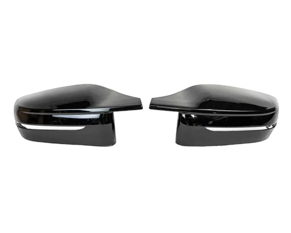Two black side mirror caps are positioned facing each other on a plain white background. Each has a glossy finish and a silver trim line near the bottom.