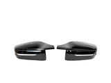 Two glossy black car side mirrors are facing each other, placed against a plain white background, highlighting their sleek design and reflective surfaces.