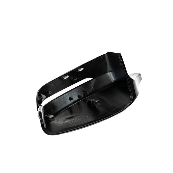 A black, unpainted car side mirror cap with attachment points sits against a plain white background, showcasing its interior features and edges.