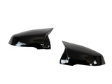 Two shiny black side mirror covers are positioned facing each other against a white background, highlighting their sleek, aerodynamic design.
