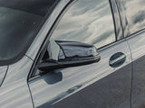 A sleek car door with a side mirror, reflecting a cloudy sky, parked on an open, deserted stretch of road.