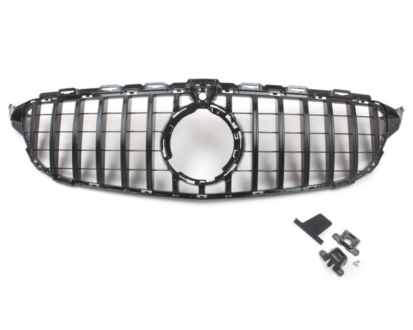 A black car grille with a circular center opening is positioned centrally; nearby, assorted mounting clips and brackets are laid out on a plain white surface.