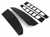 Two glossy black car spoiler pieces lay parallel, accompanied by two sets of adhesive strips with rectangular cutouts, all set against a plain white background.