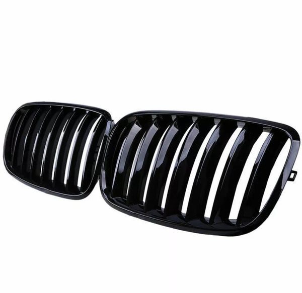 A pair of glossy black car grilles, each with vertical slats, positioned side by side against a white background.