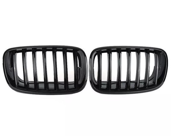 Two black car grilles with vertical slats are displayed side by side against a plain white background, showcasing a sleek automotive accessory design.