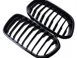 Two glossy black car grilles, each with multiple vertical slats, placed adjacent to each other against a white background.