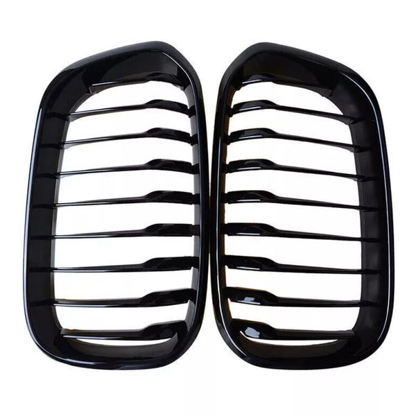 Two black kidney-shaped car grilles with horizontal slats are positioned side by side against a white background, emphasizing their glossy finish and symmetrical design.