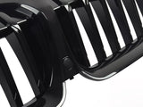 A black, glossy car grille with vertical slats is shown in close-up detail. The grille's shiny surface and precise design indicate a high-quality automotive component.