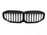 A glossy black car grille, featuring vertical slats, lies on a plain white background, designed to fit the front of a vehicle, enhancing its appearance and functionality.