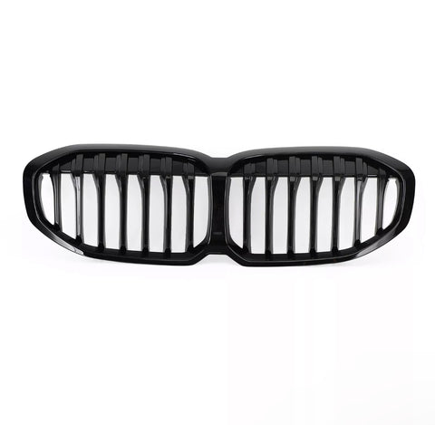 A glossy black car grille, featuring vertical slats, lies on a plain white background, designed to fit the front of a vehicle, enhancing its appearance and functionality.