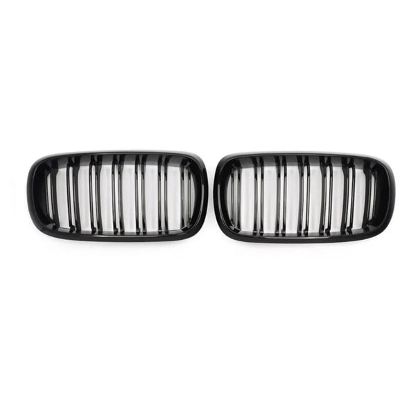Two black car grilles, each with vertical slats, are positioned side by side against a plain white background.