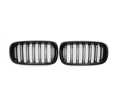 Two black car grilles, each with vertical slats, are positioned side by side against a plain white background.