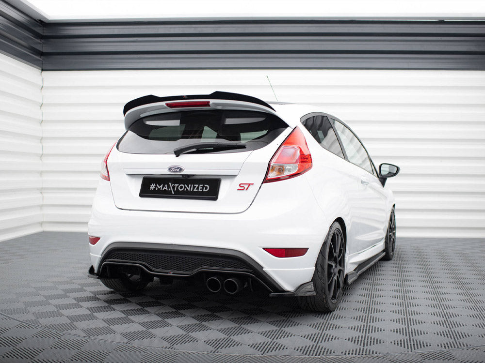 A white Ford car with "#MAXTONIZED" on its license plate is parked in a checkered room, featuring sporty black wheels and a prominent rear spoiler.