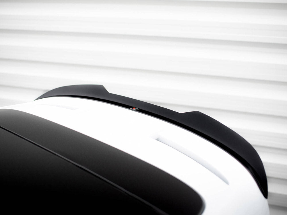 A black and white car roof with a spoiler sits stationary against a blurred horizontal line backdrop, suggesting motion or speed.