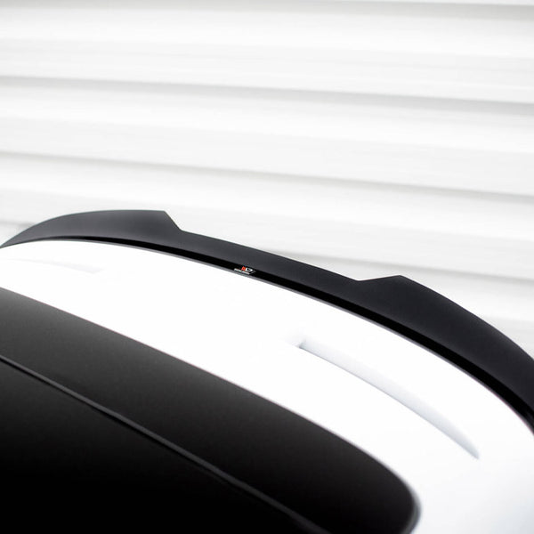 A black and white car roof with a spoiler sits stationary against a blurred horizontal line backdrop, suggesting motion or speed.