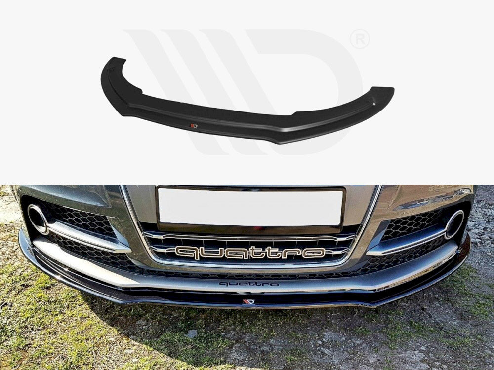 A black front lip spoiler, positioned above a car's bumper, labeled "quattro." The car is parked on grass, showcasing its detailed grille and daytime running lights.
