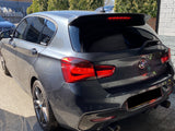 A sleek, dark gray car is parked outdoors, featuring prominent red tail lights and a BMW badge. Text on the rear reads 