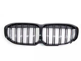 A black, dual-section car grille with vertical slats and a glossy finish is isolated against a white background, emphasizing its symmetrical design and shiny appearance.