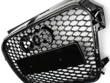 A black honeycomb grille with four interlocking rings logo is depicted. It features a rectangular plate in the center, angled against a plain white background.