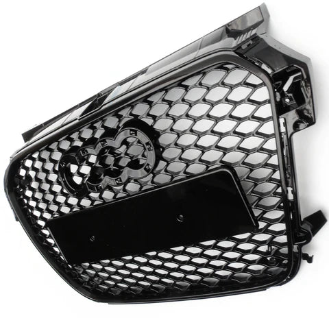 A black honeycomb grille with four interlocking rings logo is depicted. It features a rectangular plate in the center, angled against a plain white background.