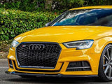 A yellow sports car is parked on a road, featuring a black grille and the Audi logo, with 